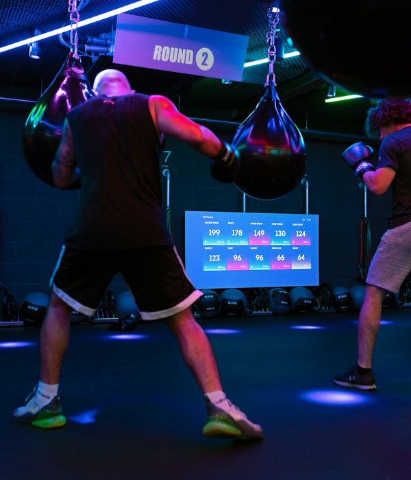 Man performing a controlled strength exercise in a dark, modern gym.